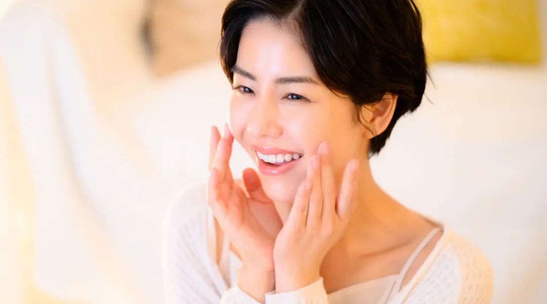 seorang wanita tersenyum menggunakan serum vitamin c yang dipakai setiap hari